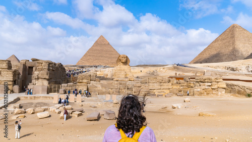 Obraz na plátně Woman traveler viewing the iconic great sphinx and vast pyramid complex, an anci