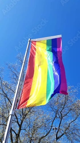 Rainbow pride flag waving in the wind against a blue sky