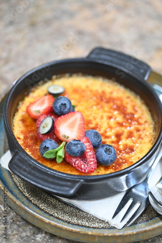 Konstfotografi French crème brûlée dessert with fresh fruit served in a black bowl