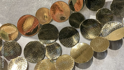 Abstract wall installation featuring shiny gold and copper metallic discs with textured wavy patterns