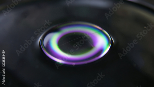 Optical phenomenon of vibrant rainbow diffraction on a dark fluid surface