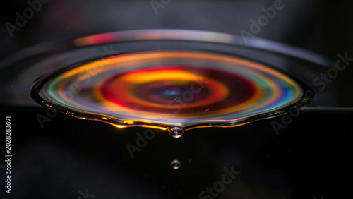 Concentric spectral rings forming a glowing vortex on a dark liquid