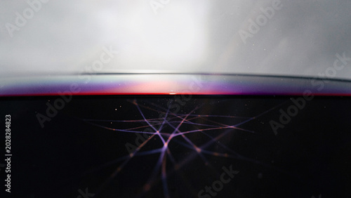 Intricate radial network of purple iridescent lines on curved liquid surface