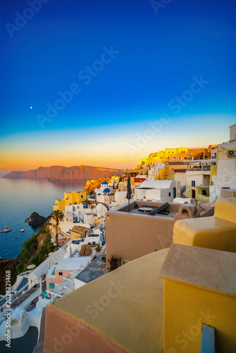 Fotografia Golden sunrise light on Oia cliffside homes