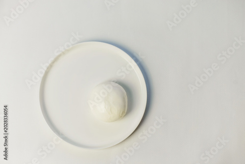 Bild auf Leinwand Round soft Mozzarella cheese on a plate against a light background