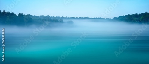 Misty forest lake at dawn with serene blue water and tranquil atmosphere