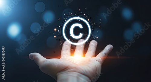Hand holding glowing copyright symbol with white outline on dark background with bokeh lights and sparks
