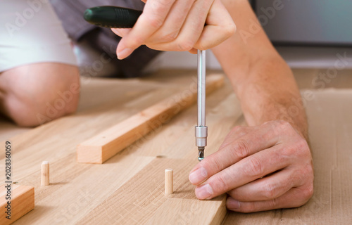 Obraz na płótnie Hands tighten a screw into a wooden board