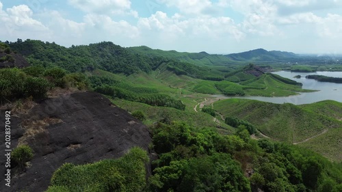 Panoramic drone view of a serene lake and rolling green hills in Vietnam.