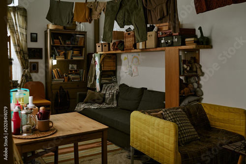 Obraz na płótnie Wide shot of cluttered living room showing clothes drying indoors, packed shelves, worn seating, conveying poverty and cramped housing