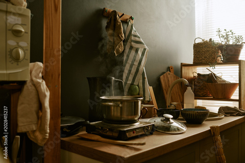 Obraz na plátne Kitchen cookware steaming on portable stove beside sink, suggesting budget home cooking and daily meal preparation