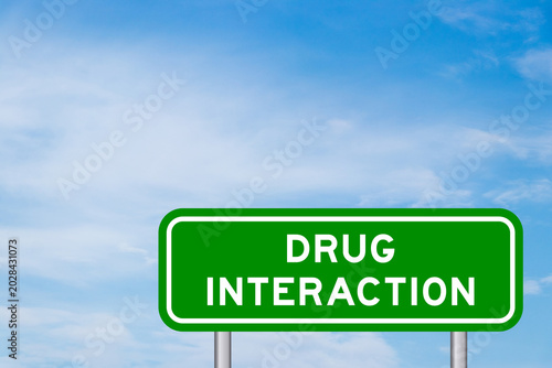 Photos Green color transportation sign with word drug interaction on blue sky with whit