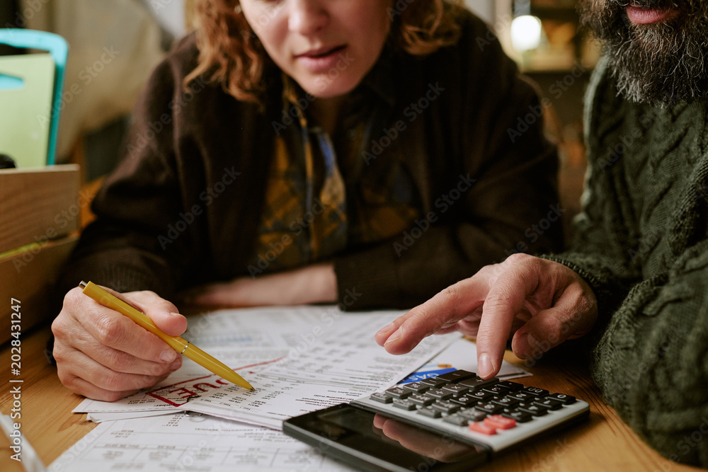 Fototapeta premium Middle aged Caucasian couple reviewing bills, calculating expenses, managing household budget and financial stress. Close up for debt, poverty, cost of living, personal finance marketing