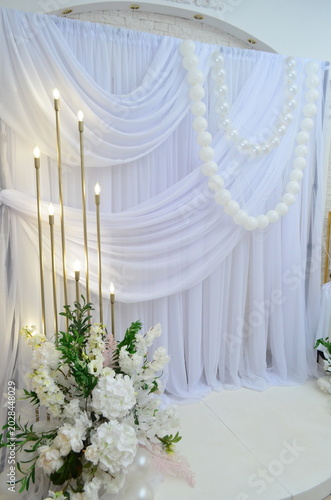 wedding photo zone made of white fabric with pearls and a candlestick