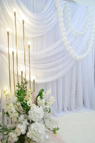 wedding photo zone made of white fabric with pearls and a candlestick