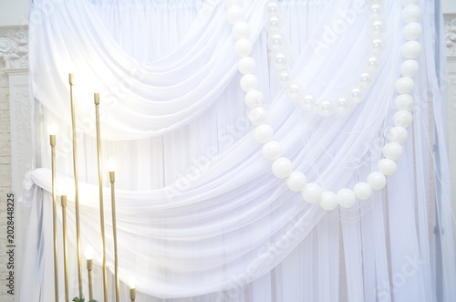 wedding photo zone made of white fabric with pearls and a candlestick