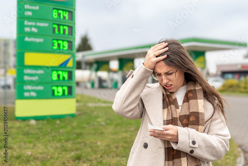High gas prices woman reading receipt at station