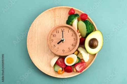 Wooden clock with healthy fresh food for intermittent fasting