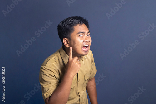 Canvas-taulu Angry man in khaki uniform pointing an index finger to his ear in annoyance on a