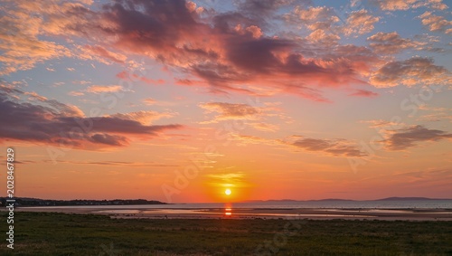 Beautiful sunset sky photo featuring warm golden hues, soft orange clouds, and a peaceful evening atmosphere. The stunning natural scenery captures the magical transition between day and night, creati