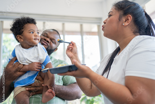 Foto Loving parents feeding their baby in a bright home environment