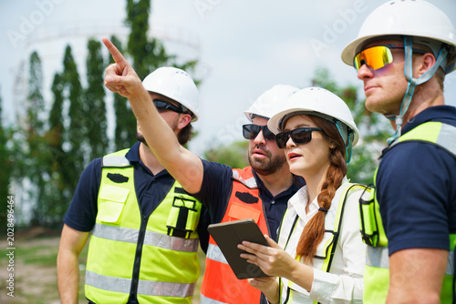 Принти на полотні Diverse factory workers in safety vests discussing data outdoor