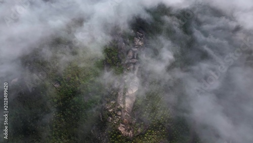Canvas-taulu Aerial view of misty forest landscape with rugged rocks and green vegetation