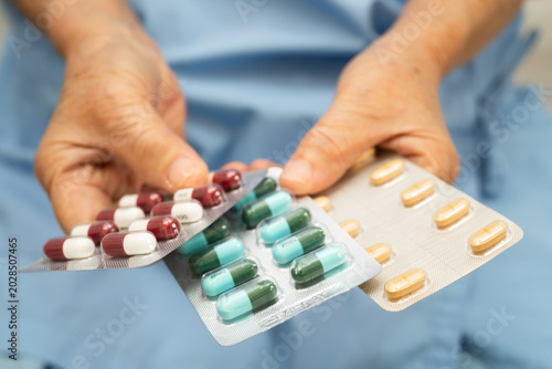 Foto Asian elderly woman holding pill drug in hand, strong healthy medical