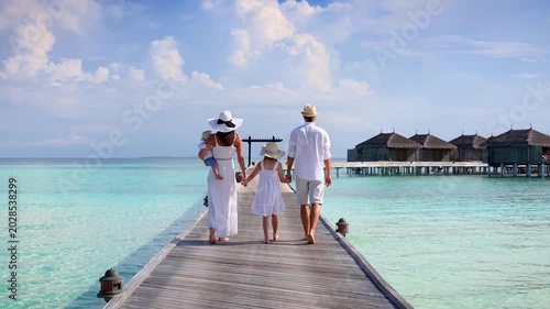 A elegant family of four enjoys their tropical vacations in the Maldives islands as a concept for travel and vacations