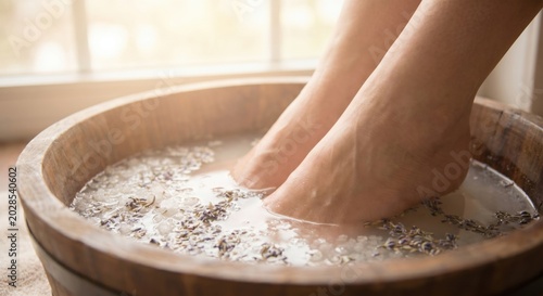 Feet soaking in wooden spa basin with lavender flowers