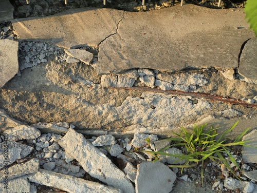 Broken concrete structure with exposed rusty rebar and crumbling cement. Detailed close-up of urban decay, construction damage and deteriorating infrastructure