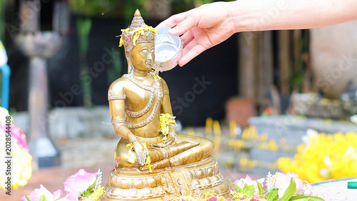 Fotografia Ritual Water Pouring Over a Golden Buddha Statue in Thailand