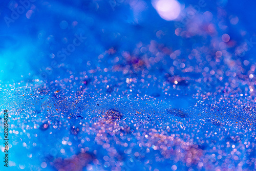 Abstract blue and purple glitter texture with soft focus bokeh. Concept of biotech beauty, molecular structure, and luxury cosmetics in a futuristic skincare setting.