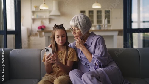 Girl teaching her grandma how to use new mobile application on smartphone