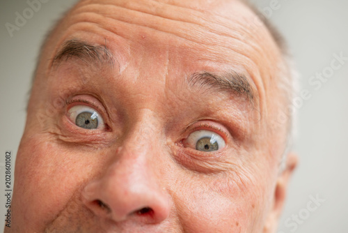 Foto Extreme close up senior man 60-65 years old, Funny or crazy expression, desperat