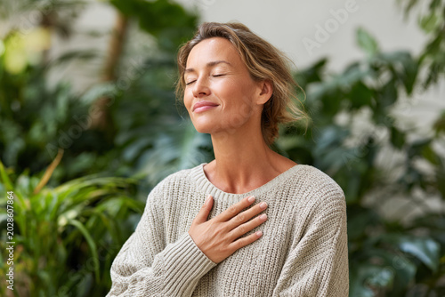 Middle aged woman practicing gratitude in indoor garden