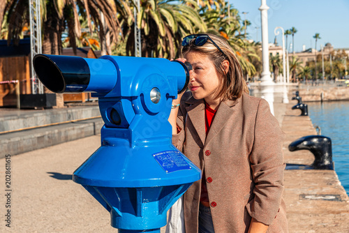 Canvas Print Woman tourist using coin operated telescope at barcelona port