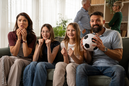 Billede på lærred Happy family watching thrilling soccer match and cheering at home