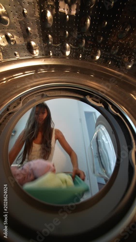 Woman arranges towels. Woman carefully places towels inside washer