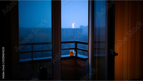 Fotografie View from balcony through glass door at dusk with distant lights, twilight