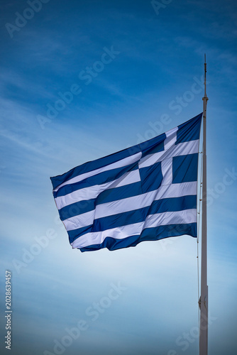 Greek flag flying on sunny day in Athens
