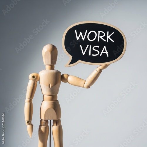 Wooden figure holds sign asking about work visa