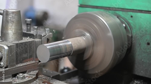 The lathe is located in the production hall. An electric lathe removes a layer from a piece of metal covered with rust, giving a picture of the product. Manufacture of metal products.
