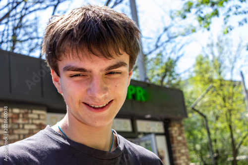 Φωτογραφία portrait of a dark-haired teenage boy on the street in the city, smiling face, h