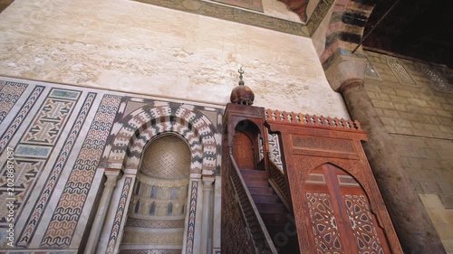 Slow motion upward camera movement revealing ornate mihrab and carved wooden minbar inside historic mosque in Cairo, Egypt. Beautiful Islamic architecture and geometric details captured in cinematic 4