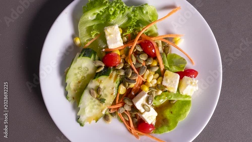 Rotating Plate of Healthy Salad with Lettuce, Carrots, Cucumbers, Tomatoes, Peppers, Feta and Sunflower Seeds 
