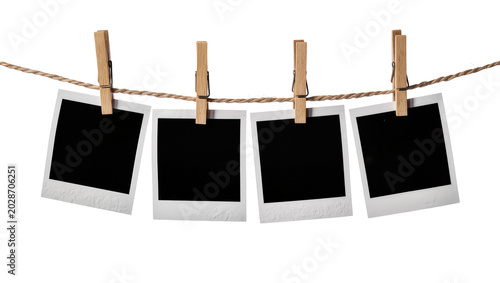 Tableau sur toile Four blank instant photo prints with wooden clothespins on a rope, isolated on t