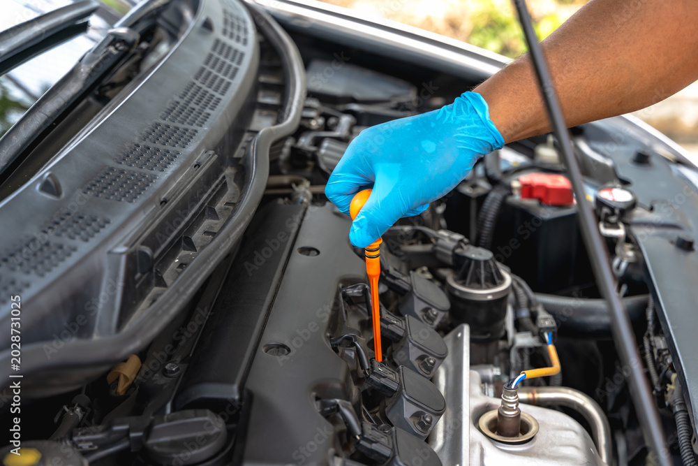 Fototapeta premium Close up unknown mechanic hands in protective gloves checking car engine in auto repair shop