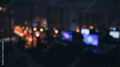 Blurred nighttime IT company office environment with modern desks and urban skyline