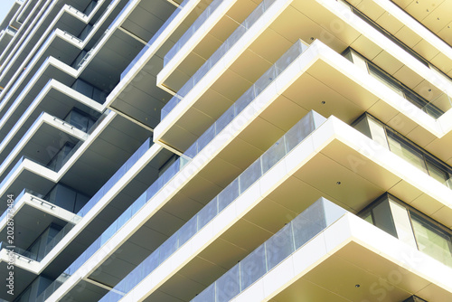 Photos Angular balcony projections with transparent railings repeating across multi-story residential structure